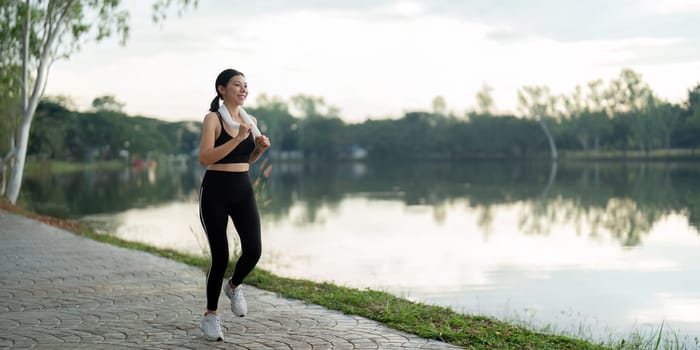 Woman running in the morning by a serene lake, promoting fitness, wellness, and a healthy lifestyle.