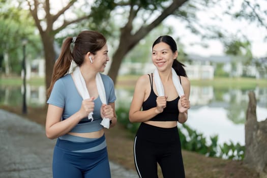 Two young women running together in a park during the morning, enjoying exercise and promoting a healthy lifestyle.