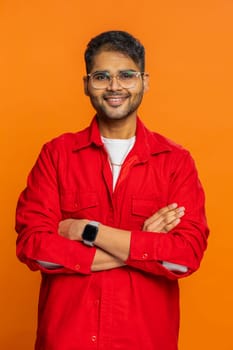 Cheerful happy young Indian man smiling friendly glad expression looking at camera dreaming resting relaxation feel satisfied good news. Arabian guy isolated on orange studio background. Vertical