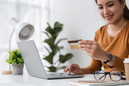 A woman uses her credit card to shop online from the comfort of her home, illustrating the ease and convenience of modern e-commerce.