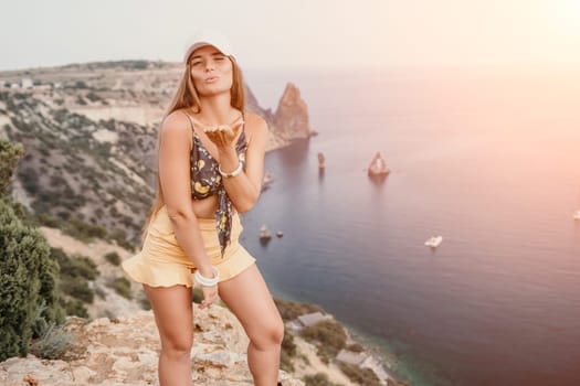 Woman travel sea. Happy tourist taking picture outdoors for memories. Woman traveler looks at the edge of the cliff on the sea bay of mountains, sharing travel adventure journey.