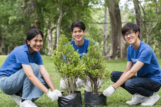 A group of cheerful volunteers planting trees in a park, showcasing teamwork and dedication to environmental conservation.