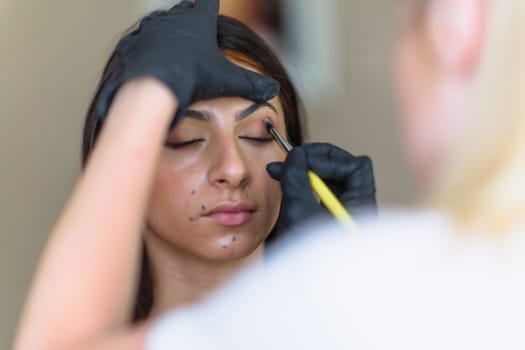 Makeup woman artist at work, professional in action with young model in beauty salon and creative classes