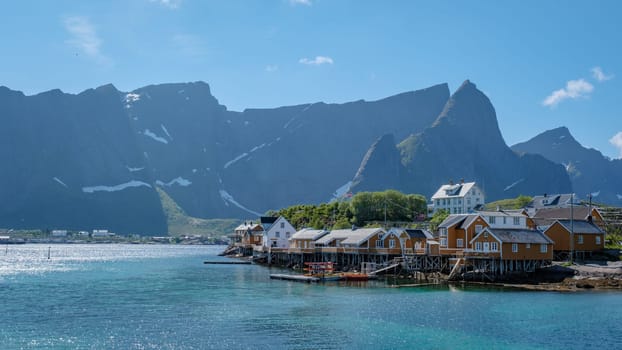 A picturesque village nestled on the coast of the Lofoten Islands in Norway, with traditional wooden houses and a backdrop of majestic mountains. Yellow fisherman Rorbuer cabins , Sakrisoy,Lofoten, Norway, Scandinavia