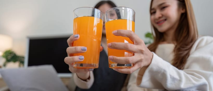 A happy lesbian couple drinking fresh orange juice together in a cozy home environment, promoting a healthy lifestyle and love.