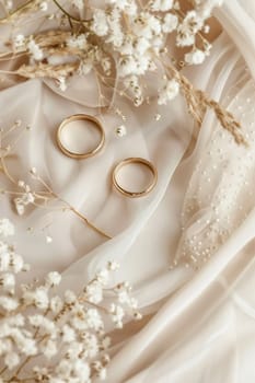 A serene wedding background featuring two golden rings elegantly placed on a delicate fabric with dried white flowers, creating a soft and romantic atmosphere with plenty of copy space. Generative AI