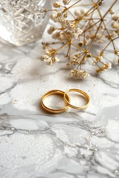 Elegant wedding still life of two golden rings on marbled background with delicate dried flowers and subtle glitter, perfect for invitations and romantic displays with ample copy space. Generative AI