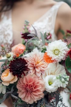 Bride holding a vibrant boho style bouquet. The image focuses on the rich texture and color of the flower. Generative AI