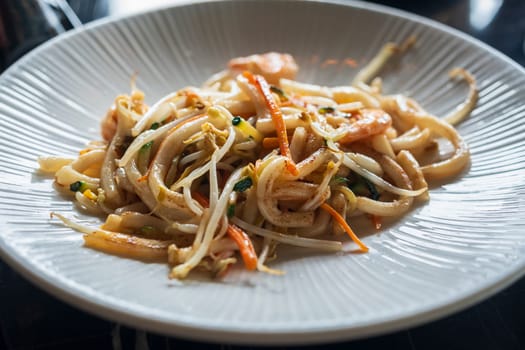 Stir-fried Yaki Udon noodles with shrimps seafood, vegetables and soy-based sauce at restaurant. Japanese food.close up.