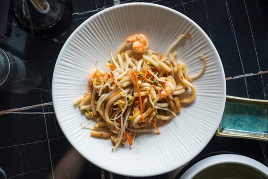 Top view of stir-fried Yaki Udon noodles with shrimps fish, vegetables and soy-based sauce at restaurant. Japanese food.