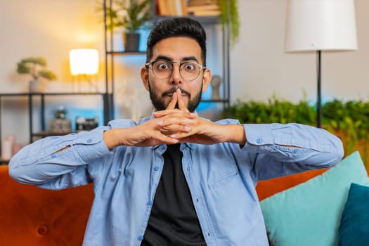 Portrait of amazed shocked Indian man wearing eyeglasses with wow reaction open mouth in living room at home. Happy surprised Hispanic guy with big eyes, shocked by sudden victory, good win news