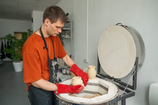 Caucasian man loading ceramic products into a special kiln