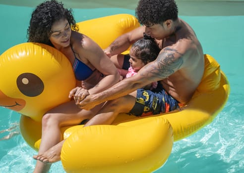 Dominican family on rubber duck raft in swimming pool enjoying holidays in summer time.