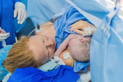 Baby on mother's chest immediately after birth in a hospital. The mother and newborn share a tender moment, emphasizing the bond and emotional connection. The medical staff ensures a safe and caring environment.