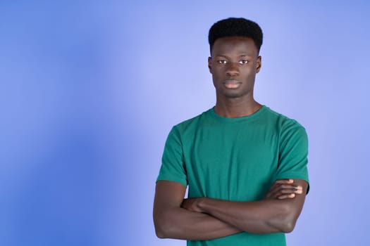 A man wearing a green shirt is standing with his arms crossed.