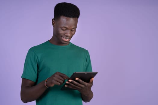 A man wearing a green shirt is looking intently at a tablet device in hand.