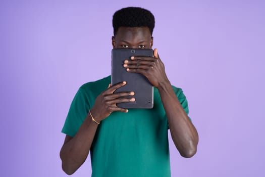 A man holding a tablet in front of his face, concealing his features.