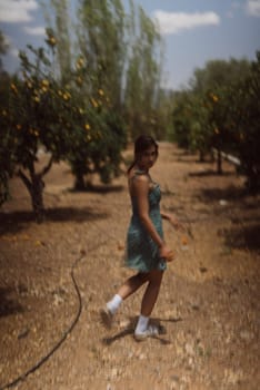 A young woman enjoys a leisurely stroll through a sunlit orchard, surrounded by nature and serenity