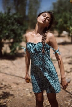 A young woman in a blue polka dot dress stands outdoors, embodying summer fashion and outdoor lifestyle