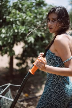 A young woman with braided hair in summer dress pulls a cart outdoors on a sunny day, enjoying leisurely activity