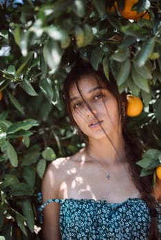 A woman in an orange grove under sunlight exudes tranquility and beauty, set against a backdrop of vibrant nature