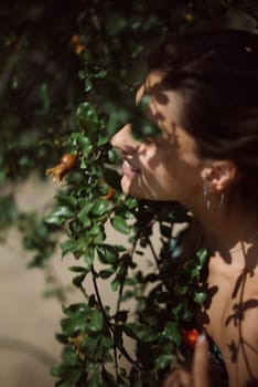 A serene image of a woman surrounded by green leaves, with the suns shadows dancing on her face outdoors
