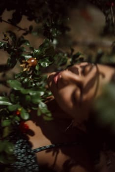 Portrait of a woman with closed eyes surrounded by leaves and sunlight creating a serene, nature-inspired scene.