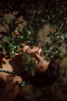 A woman smiles in an orchard, enjoying the greenery and fresh fruits on a sunny day, surrounded by natural vibes