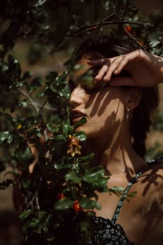 A woman in an artistic photo partly obscured by leaves, with shadowy face, creating a captivating atmosphere