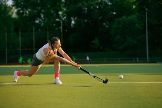 girl hockey player plays field hockey on a sunny day, female hockey player hits the ball with a stick, field hockey concept