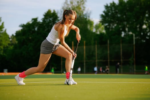 girl hockey player plays field hockey on a sunny day, female hockey player hits the ball with a stick, field hockey concept