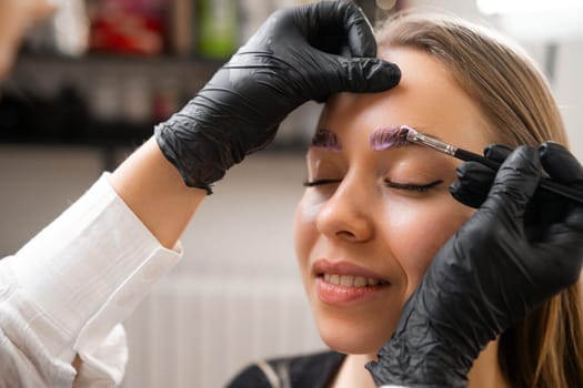 A woman is having her eyebrows laminated by a professional