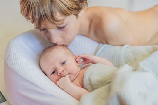 Older brother kisses newborn baby brother. This heartwarming moment captures the sibling bond and love, highlighting family connections and the tender care of an older sibling for the newest family member.