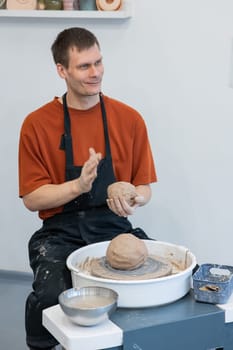 A potter kneads clay before using it on the potter's wheel. Vertical photo