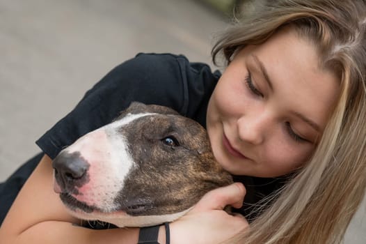 Portrait of caucasian woman hugging her bull terrier dog outdoors