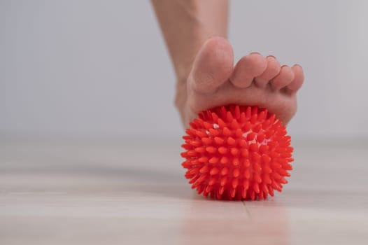 Close-up of a woman's foot on a massage ball with spikes