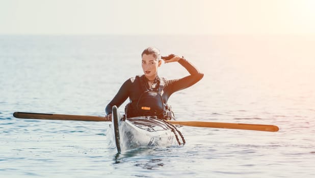 Happy smiling woman in kayak on ocean, paddling with wooden oar. Calm sea water and horizon in background