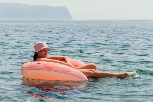 Summer Vacation Woman in hat floats on an inflatable donut mattress, a water toy swim ring. Unrecognizable young woman relaxing and enjoying family summer travel holidays vacation on the sea