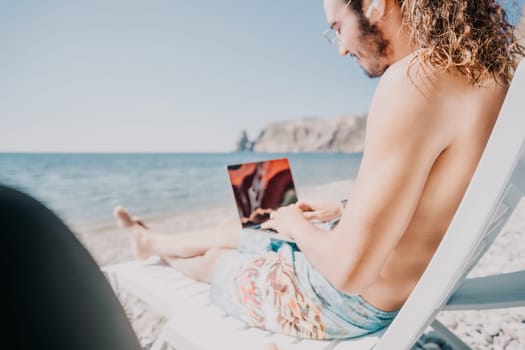 Digital nomad, Business man working on laptop by the sea. Man typing on computer by the sea at sunset, makes a business transaction online from a distance. Freelance, remote work on vacation