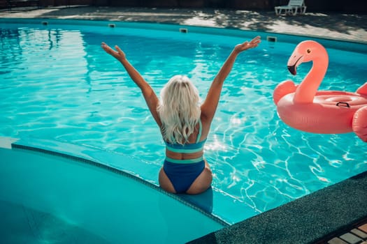 Happy woman in bikini sitting near swimming pool, summer vacation