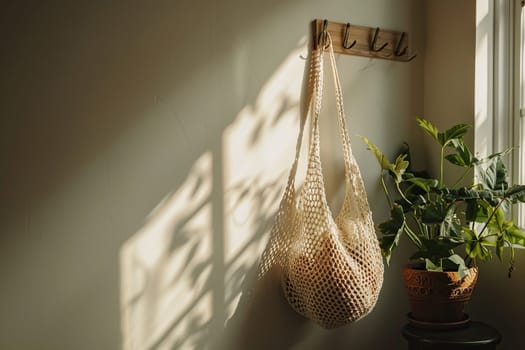 Mesh string bag hanging on a hook on a white wall with shadows.