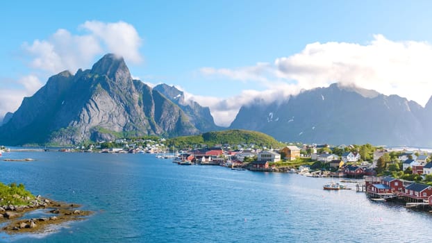 A panoramic view of a charming village nestled amidst towering mountains and a sparkling fjord in Norway. Reine, Lofoten, Norway