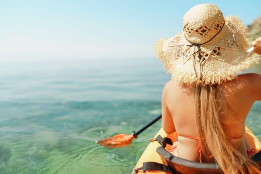 Woman in kayak back view. Happy woman with long hair in a swimsuit and hat floating in kayak on the sea. Summer holiday vacation. Summer holidays vacation at sea