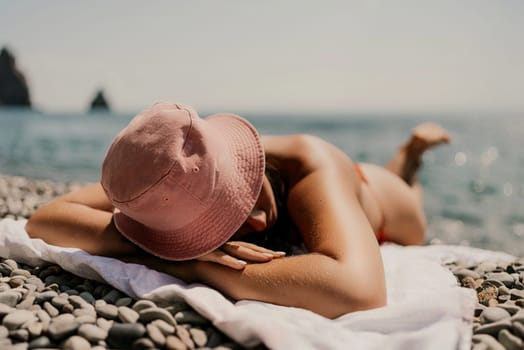 A woman sunbathes on the beach, lying on her stomach in a red swimsuit against the sea backdrop