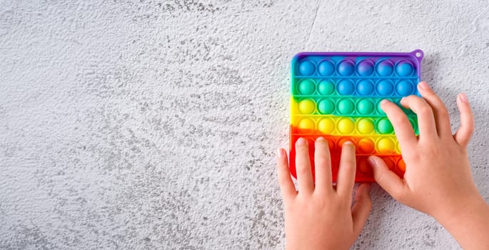 Top view of rainbow antistress sensory toy fidget push pop it on stone background