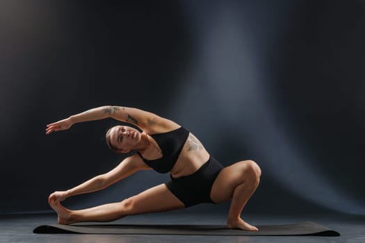 girl doing yoga and stretching, yoga and stretching poses on a dark background, yoga practice. fighting excess weight losing weight