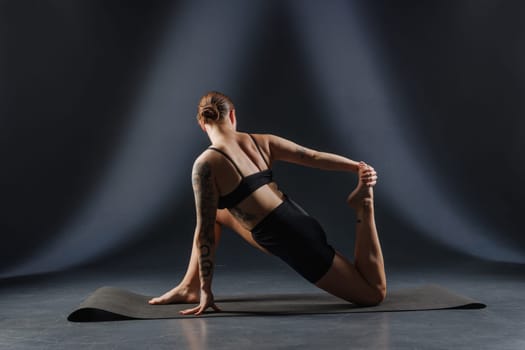 girl doing yoga and stretching, yoga and stretching poses on a dark background, yoga practice. fighting excess weight losing weight