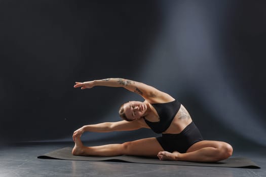 girl doing yoga and stretching, yoga and stretching poses on a dark background, yoga practice. fighting excess weight losing weight