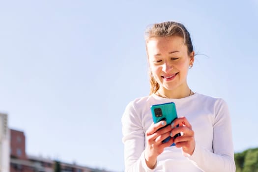 smiling caucasian woman using mobile phone, concept of technology of communication and social media, copy space for text