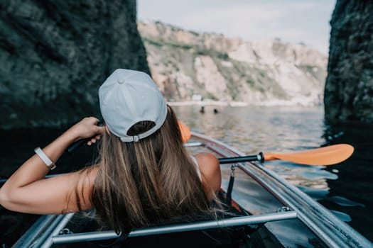 Woman in kayak back view. Happy young woman with long hair floating in transparent kayak on the crystal clear sea. Summer holiday vacation and cheerful female people having fun on the boat.